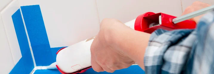 Person verwendet Silikonpistole im Badezimmer.